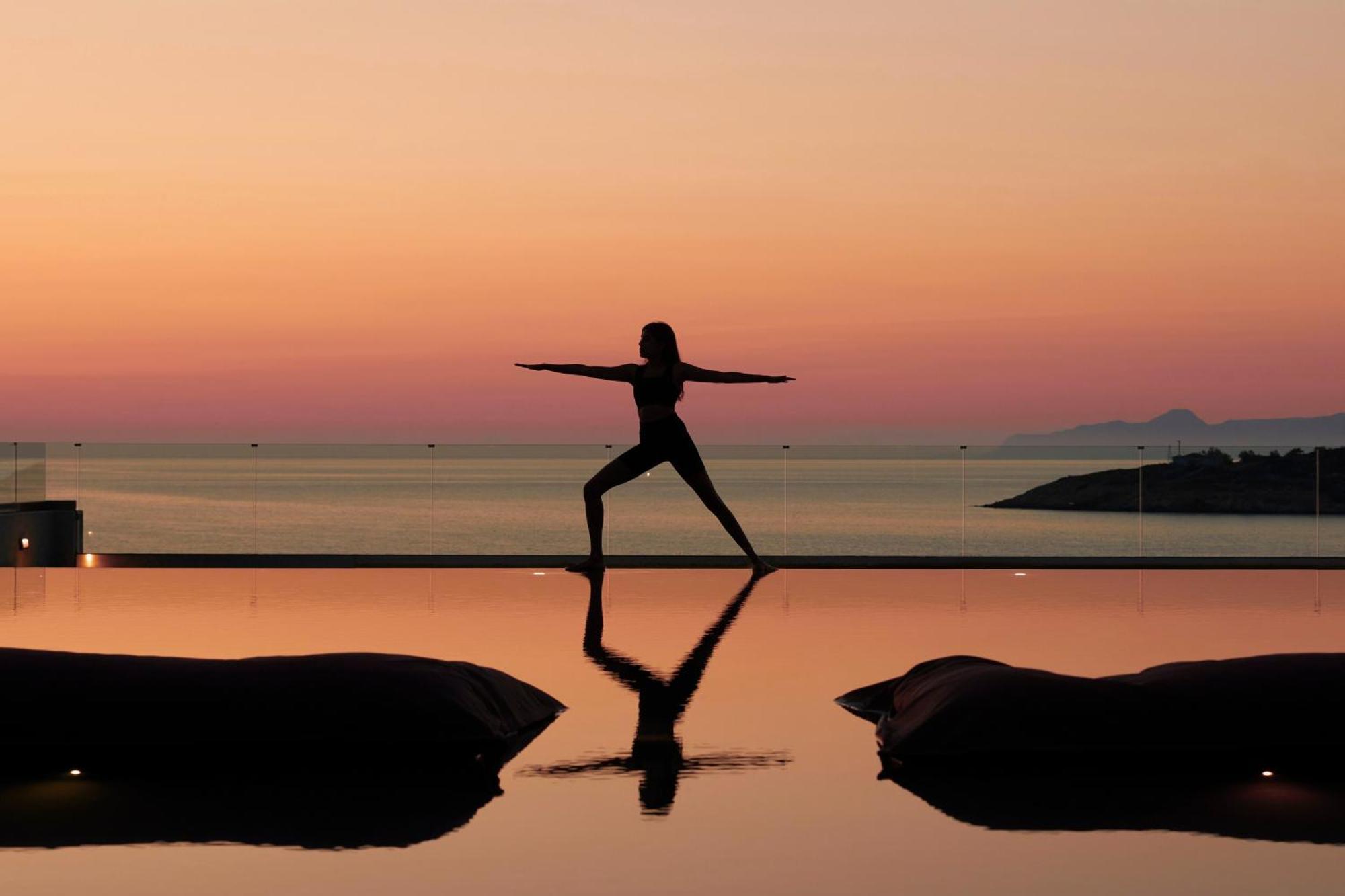 Minos Palace Resort - Adults Only Agios Nikolaos  Bagian luar foto A woman practicing yoga at sunset